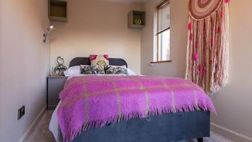 Un dormitorio con cama, mesita de noche, decoración en la pared y una ventana.