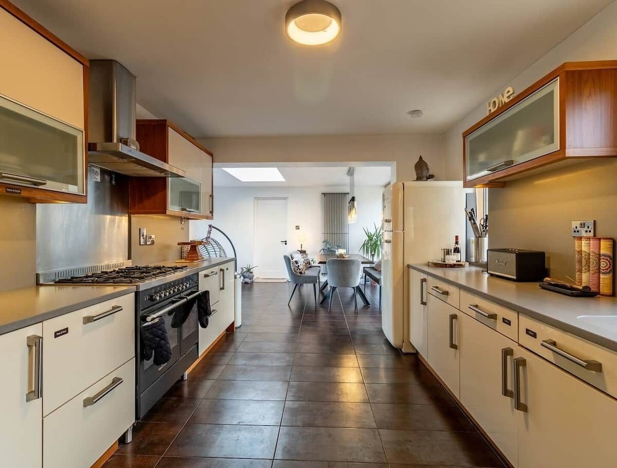 Una cocina moderna con estufa, horno y microondas. Hay una zona de comedor con una mesa y sillas. La cocina tiene armarios y una encimera.