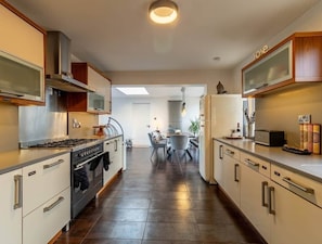 A modern kitchen with a stove, oven, and microwave. There is a dining area with a table and chairs. The kitchen has cabinets and a countertop.