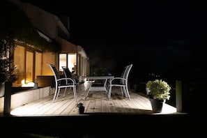An outdoor patio with a table and chairs, a fire feature, and potted plants.