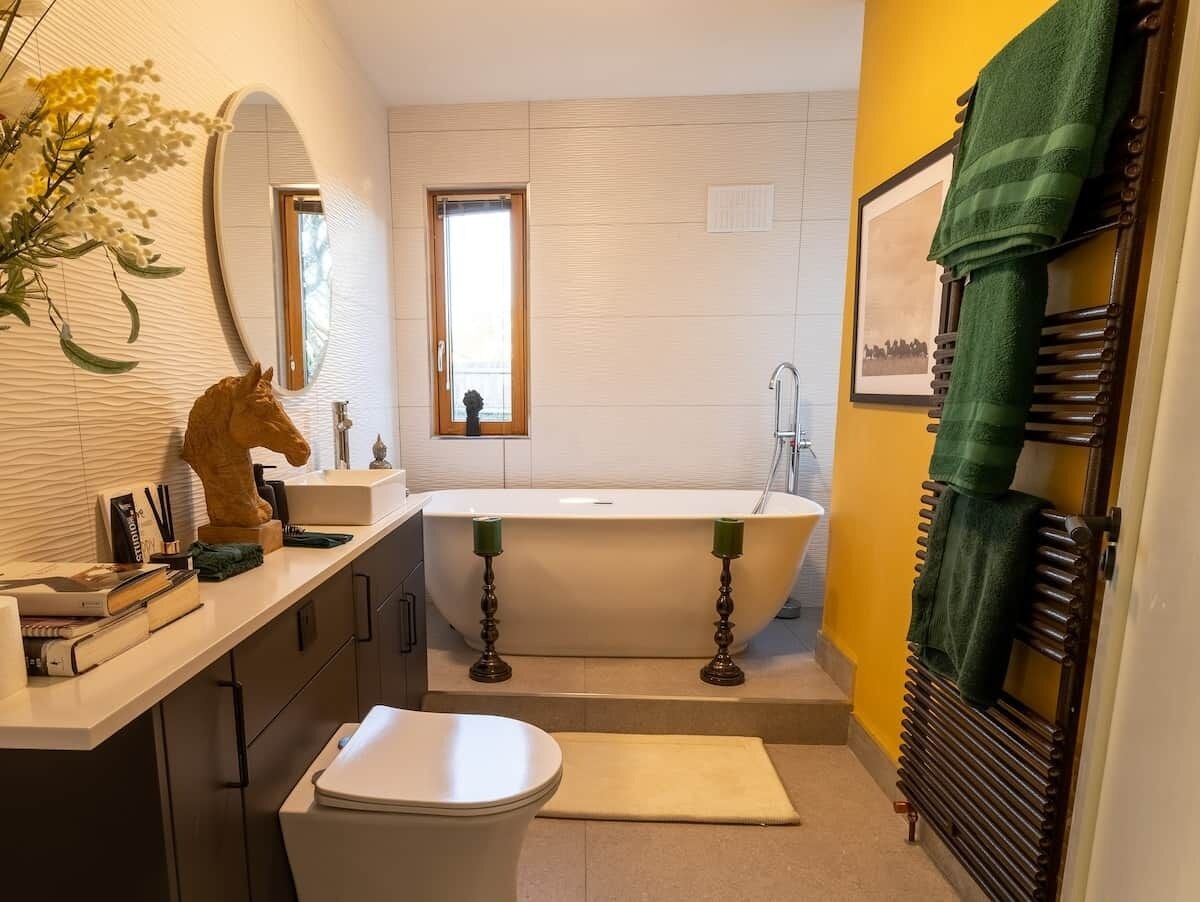 A bathroom with a bathtub, a toilet, a sink, and a vanity with a mirror.
