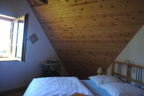 A room with a sloped ceiling, a bed with white bedding, a small table with a lamp, and a window with an open shutter. - Holiday home in Sasino with swimming pool (Sasino)