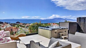 A rooftop terrace with outdoor furniture, a hot tub, and a view of the sea and distant mountains. - Stunning  villa for 8 people with WIFI and terrace (Ardrossan)
