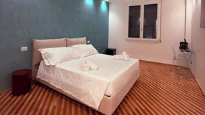 Un dormitorio con cama, ventana y piso de madera.