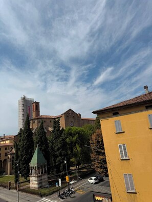 Un edificio histórico con una imponente torre de campanas, rodeado de árboles y edificios modernos.