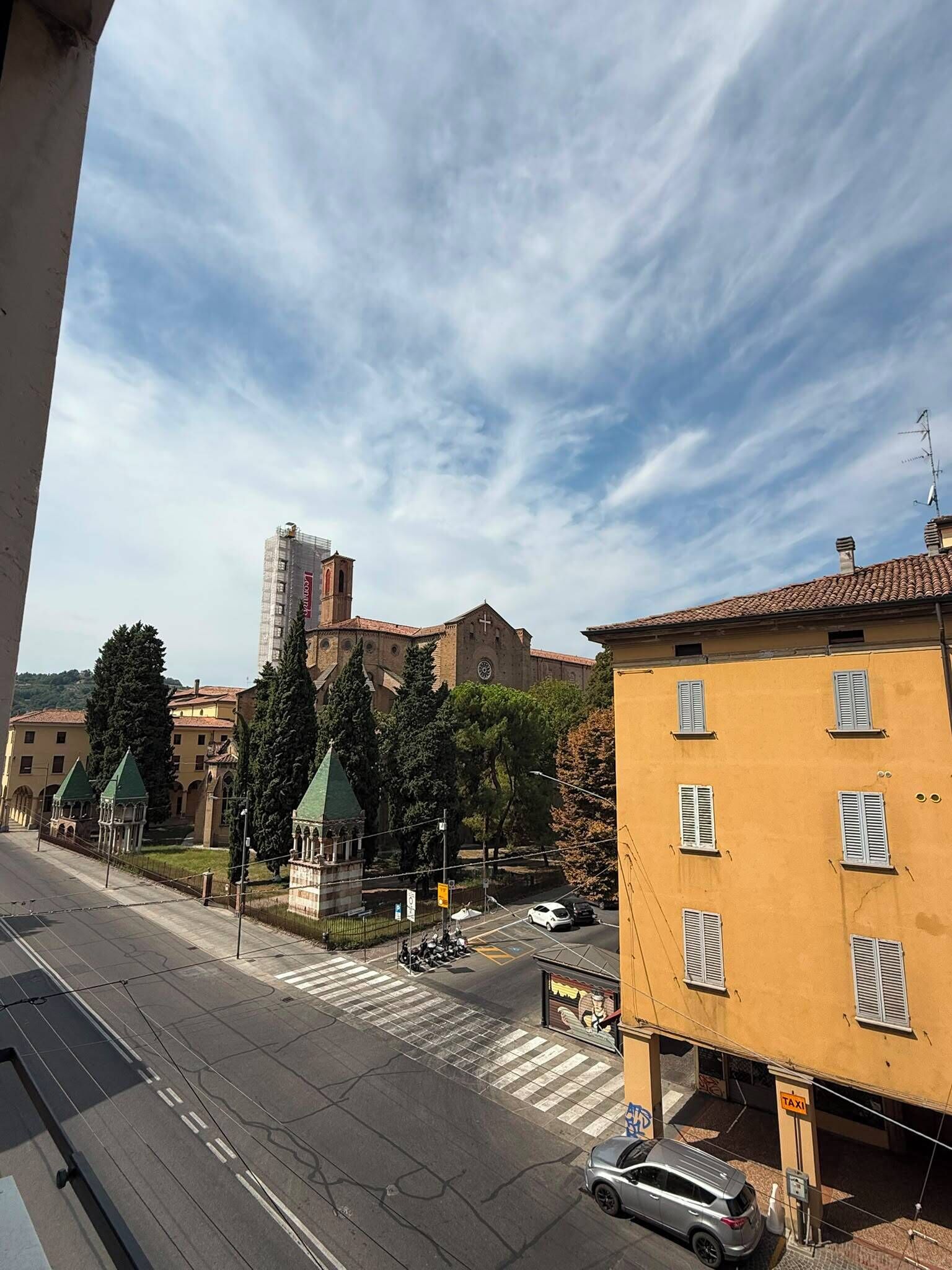 A street view with a church, a tower, and a yellow building with shutters.