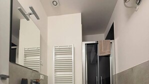 Un baño moderno con inodoro, tocador con espejo y cabina de ducha.