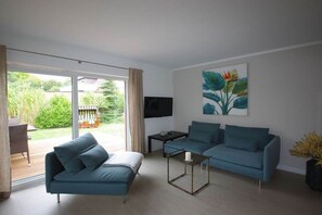 Ein modernes Wohnzimmer mit einer Couch, einem Couchtisch und einem Flachbildfernseher.