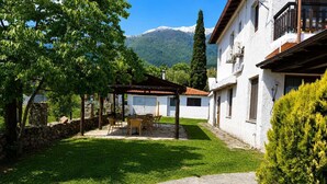 A courtyard with a pergola, outdoor seating, a stone pathway, and a mountain backdrop. - Zidoron House - Peaceful Retreat at Lake Kerkini (Mandraki)
