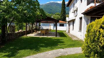 A courtyard with a pergola, outdoor seating, a stone pathway, and a mountain backdrop.