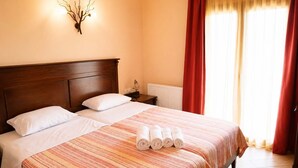 A hotel room with a large bed, two pillows, a nightstand with a lamp, and a wall-mounted light fixture. - Zidoron House - Peaceful Retreat at Lake Kerkini (Mandraki)