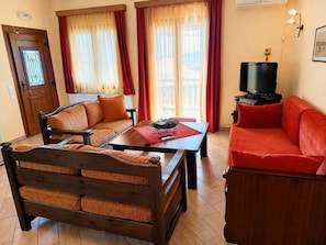 Una sala de estar amoblada con un sofá, un sofá rojo, una mesa de centro de madera y un televisor.