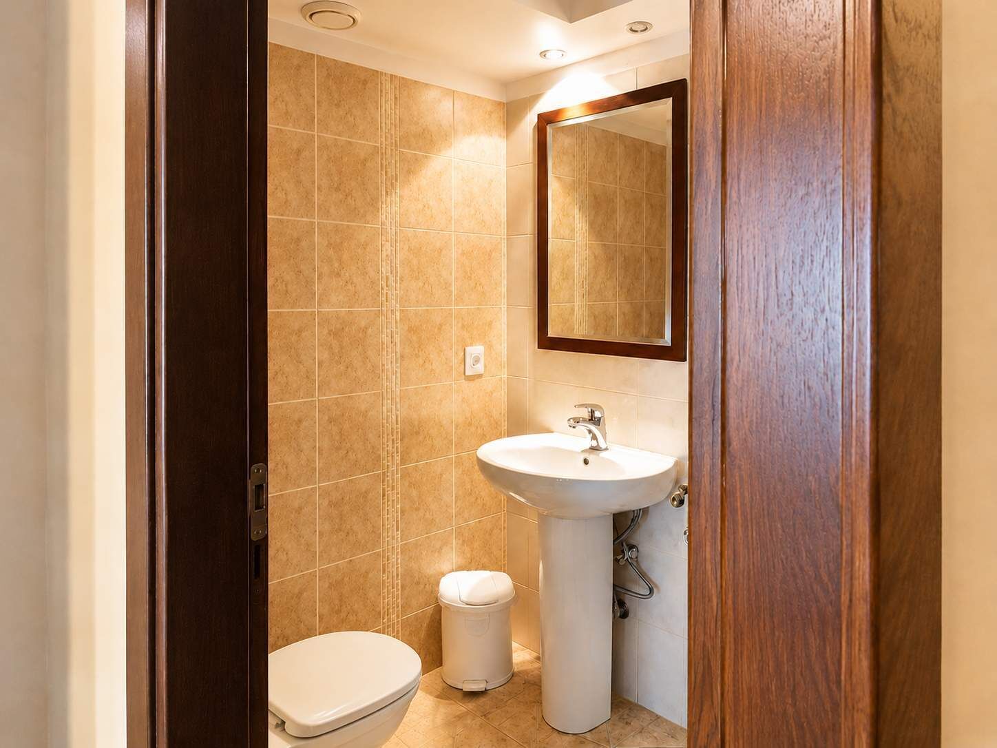 A small bathroom with a toilet, sink, and mirror.