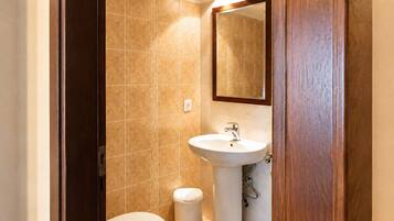A small bathroom with a toilet, sink, and mirror.