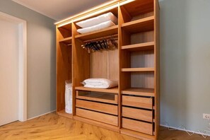 Ein Holzschrank mit mehreren Einlegeböden und Schubladen, einer Kleiderstange und einer Leuchte über dem obersten Fach.