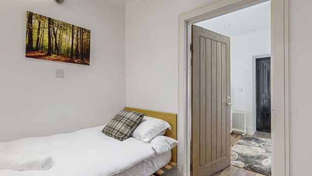 A bedroom with a bed, a door, and a painting on the wall. - Stunning  villa for 4 guests with pets allowed (Isle Of Bute)