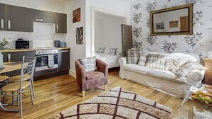 A compact living space with a kitchenette, a dining area, a sofa, and a patterned rug. - Stunning  villa for 4 guests with pets allowed (Isle Of Bute)