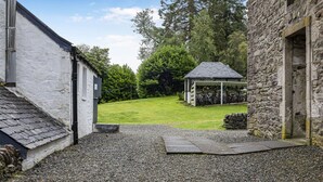 A courtyard with a stone building, a white building, and a gazebo. - Stunning  villa for 4 guests with pets allowed (Isle Of Bute)
