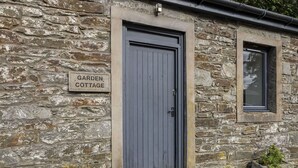 A stone cottage with a grey door and a window. A sign above the door reads 'Garden Cottage.' - Stunning  villa for 4 guests with pets allowed (Isle Of Bute)