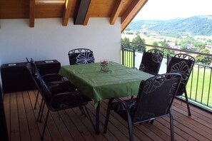 Un balcón con mesa y sillas, con vistas a un paisaje pintoresco.