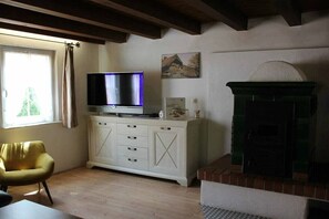 A room with a television on a cabinet, a fireplace, and a window with curtains. - ||------------------storage building------------|| (Hornberg)