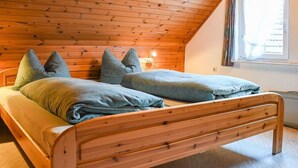 A wooden bed with a sloped ceiling in a room with a window. - ||------------------storage building------------|| (Hornberg)
