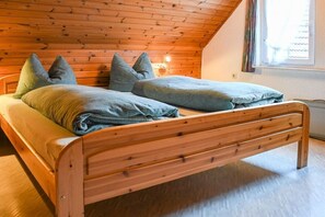A wooden bed with a sloped ceiling in a room with a window. - ||------------------storage building------------|| (Hornberg)