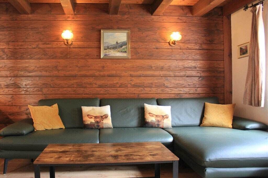 A green leather sofa with three cushions, a wooden coffee table, and two wall-mounted lights.