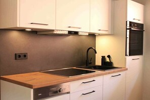 A modern kitchen with white cabinets, a wooden countertop, a built-in oven, and a dishwasher. - ||------------------storage building------------|| (Hornberg)