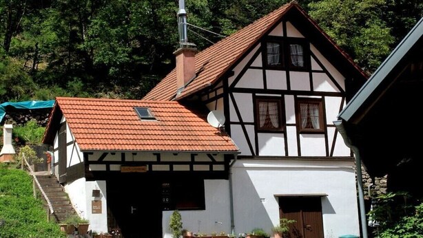 A traditional half-timbered house with a red-tiled roof, a chimney, and a small satellite dish. - ||------------------storage building------------|| (Hornberg)