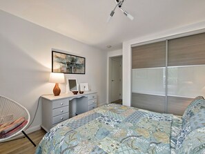 A bedroom with a bed, a chair, a desk with a lamp, a painting, and a sliding door. - Lovely apartment for 4 people with WIFI and TV (Alexandria)