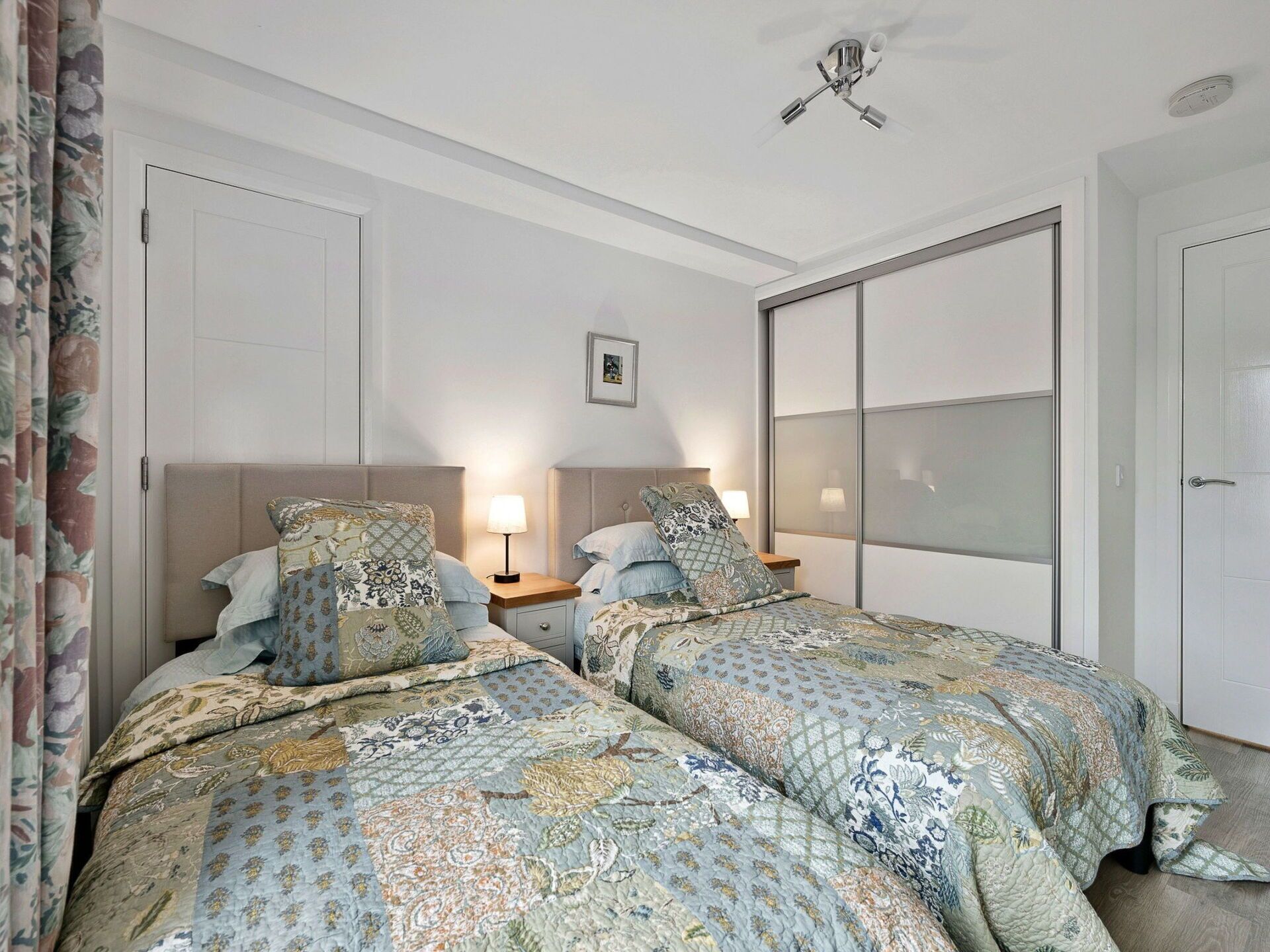Ein Schlafzimmer mit zwei Betten, einem Deckenventilator und einer großen Schiebetür.