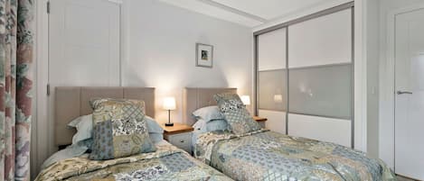 Ein Schlafzimmer mit zwei Betten, einem Deckenventilator und einer großen Schiebetür.