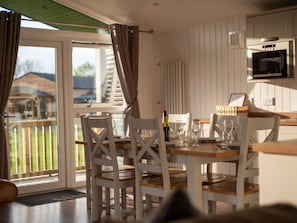 A dining area with a table set for four, white chairs, and a view of the outdoors through a glass door. - Beautiful private villa for 6 people with WIFI and terrace (Perth)