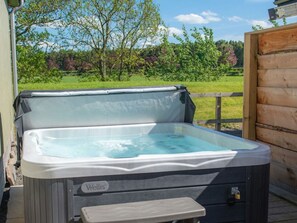 Een hottub met een houten terras en een houten omheining op de achtergrond.