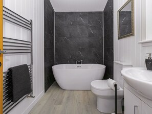Een moderne badkamer met een vrijstaand bad, een toilet en een wastafel.