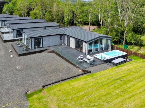 Een modern woonhuis met zwembad, overdekt terras en een groot gazon.