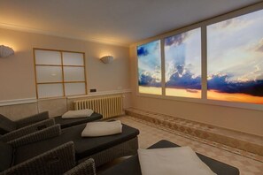 A spa room with massage tables, a large window with a sunset view, and a decorative wall panel. - Holiday apartment in Sylt with 1 bedroom (Wenningstedt)