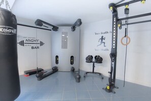Ein Fitnessraum mit einem Sandsack, Gewichte und einer Klimmzugstange.