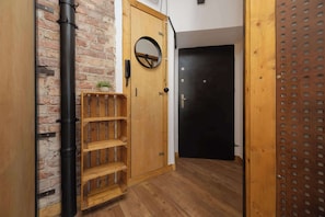 A wooden door with a round mirror, a black door, and a shelf unit. - Loft Apartment in Warsaw | Close to Metro | Pet Friendly (Warszawa)