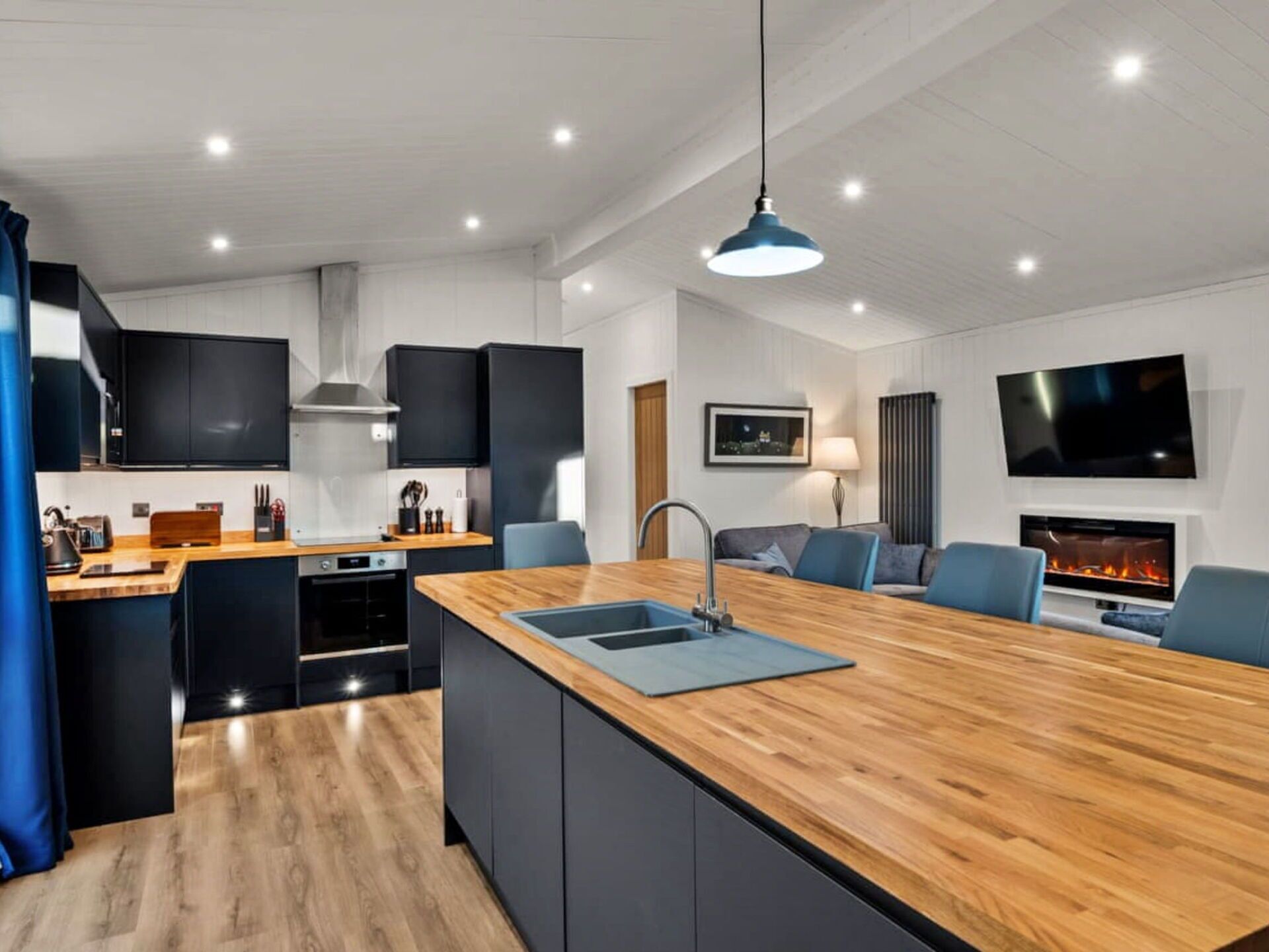 Una cocina moderna con una isla central, electrodomésticos integrados y un televisor de pantalla plana en la pared.