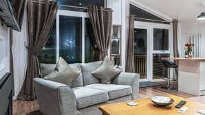 Een moderne woonkamer met een grijze bank, een houten salontafel en uitzicht op buiten.