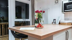 Een moderne keuken met een houten aanrecht, een barkruk, een fles champagne, aardbeien en een vaas rode rozen.