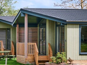A cabin with a porch, wooden deck, and a small garden area.