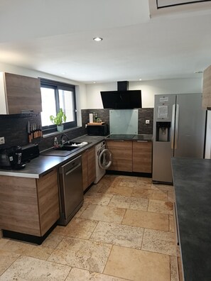 A modern kitchen with a built-in washing machine, a microwave, and a refrigerator. - Quiet country home (Pernes-les-Fontaines)