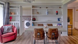 Eine moderne Küche mit weißen Schränken, einem Esstisch mit zwei Stühlen, einem roten Sofa und einem Waschbereich mit einer Waschmaschine.
