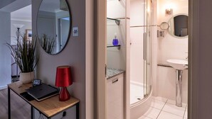 Ein modernes Badezimmer mit einer gläsernen Duschkabine, einem runden Spiegel und einem kleinen Waschbecken.