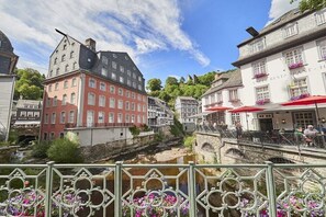 Blick auf einen Fluss mit historischen Gebäuden, einem Café und einer Brücke.