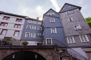 A multi-story building with a stone archway entrance, multiple windows, and a staircase leading to an upper level. - Holiday apartment with 2 bedrooms (Monschau)