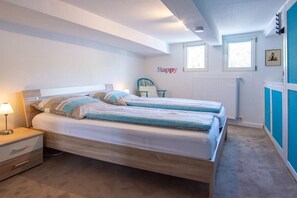 Ein Schlafzimmer mit zwei Betten, einem Nachttisch, einem Sessel und einer Heizung.